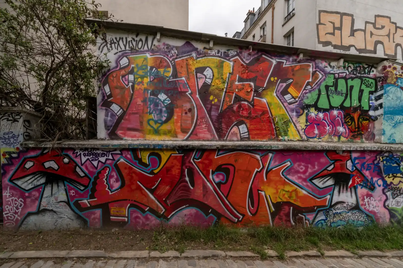 Un mur de rue parisien couvert de graffitis colorés avec des lettres stylisées.