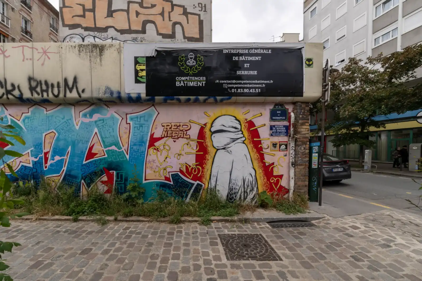 Une enseigne de chantier et des graffitis décorent un mur de rue parisien.