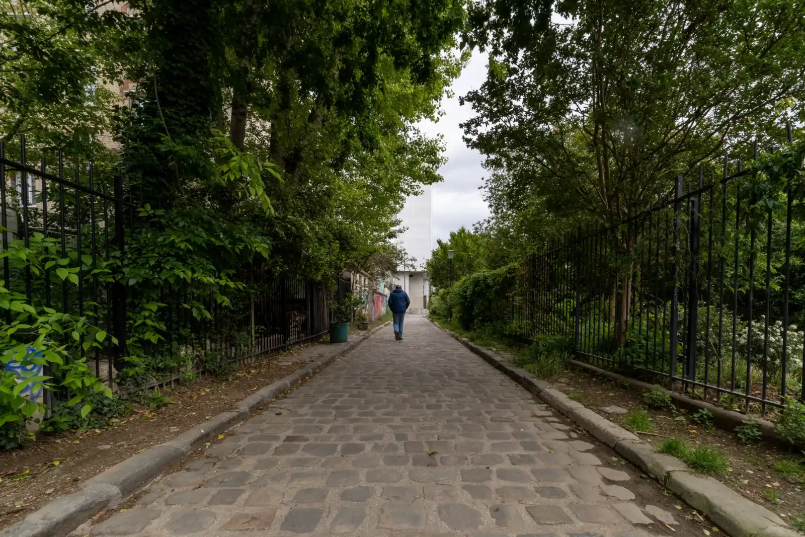 Une personne marche seule sur les pavés de la charmante rue des Thermopyles.