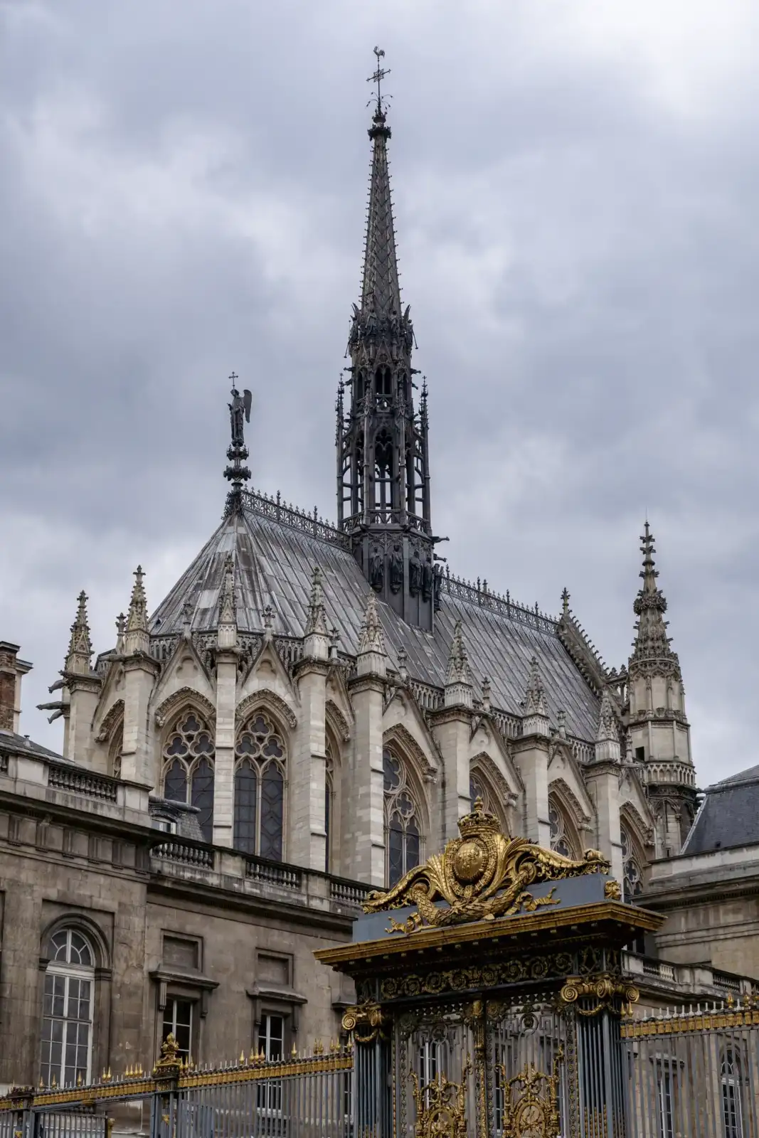 La flèche gothique de la Sainte-Chapelle se dresse fièrement sous un ciel parisien gris.