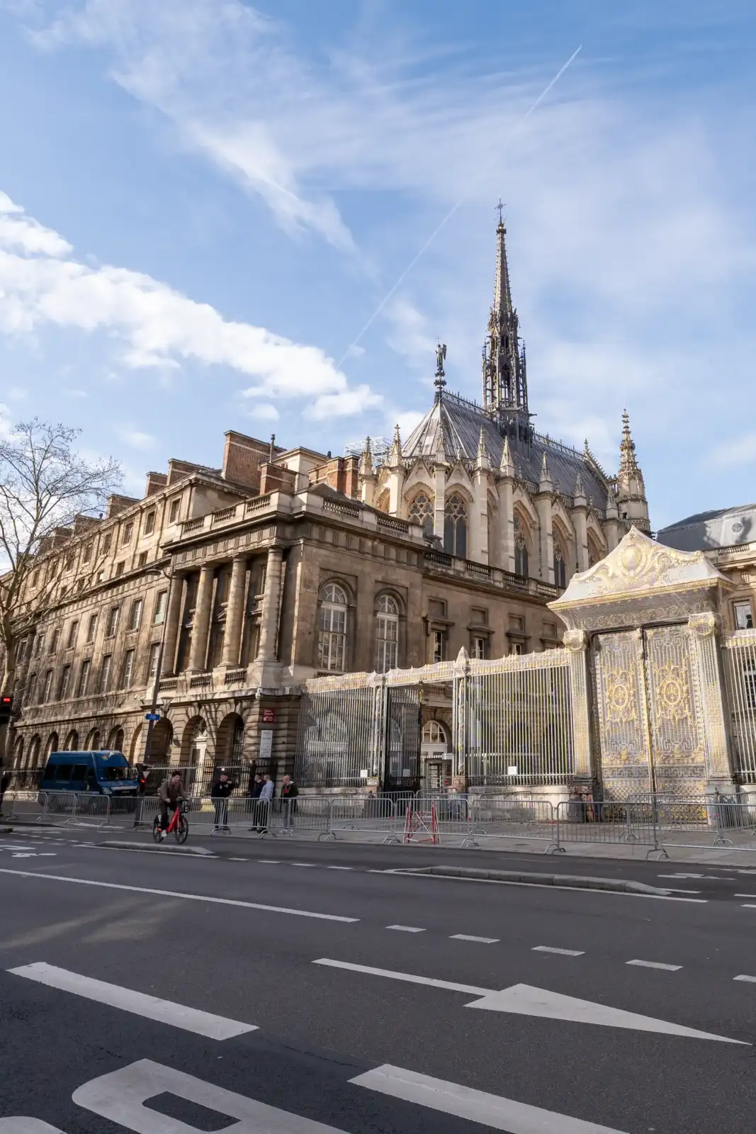 La façade gothique de la Sainte-Chapelle domine une rue parisienne sous un ciel bleu.