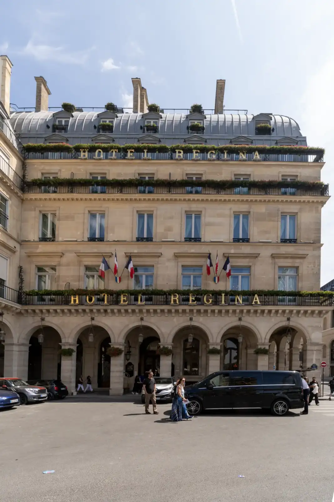Façade classique et élégante de l'Hôtel Regina sous un ciel partiellement dégagé.