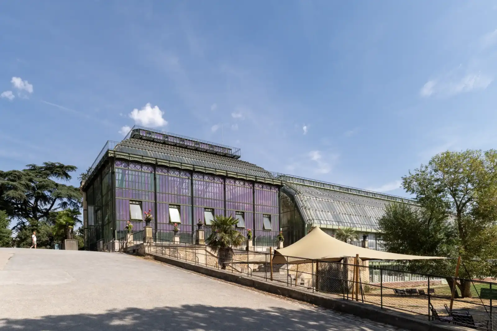 Vue extérieure des grandes serres du Jardin des Plantes à Paris sous un ciel bleu.