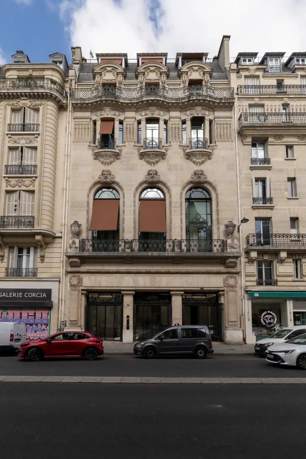 Vue de la façade principale du siège parisien de Jean Paul Gaultier avec des voitures garées.