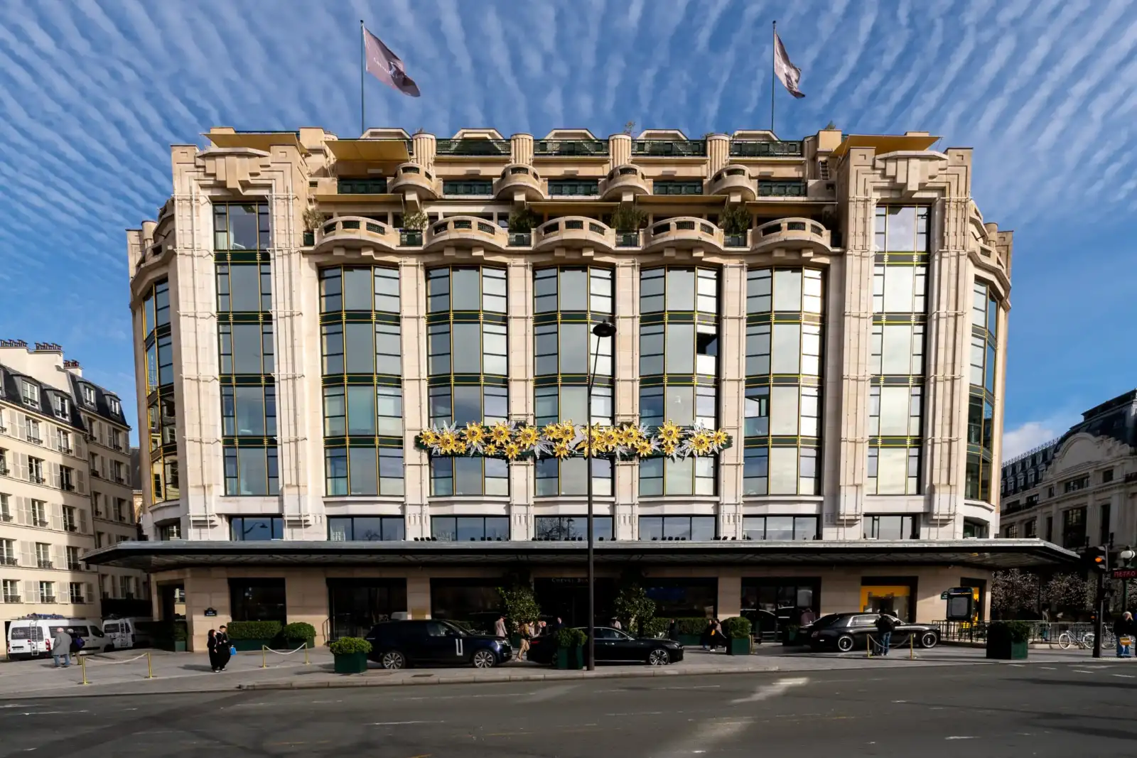 La façade majestueuse de l'hôtel Cheval Blanc Paris sous un ciel bleu nuageux.