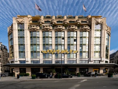La façade majestueuse de l'hôtel Cheval Blanc Paris sous un ciel bleu nuageux.