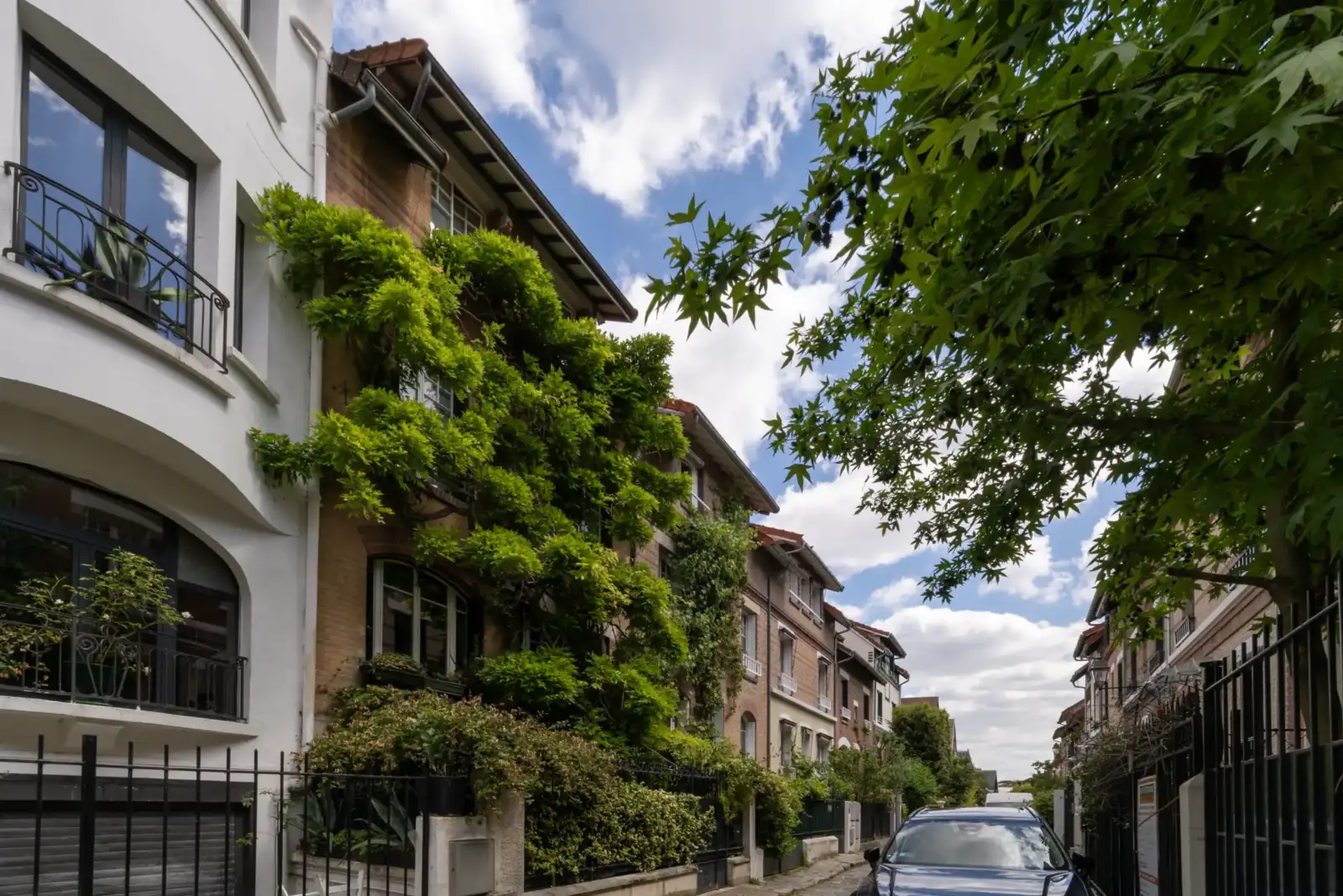 Des maisons bordent une rue calme et verdoyante du square Montsouris à Paris.