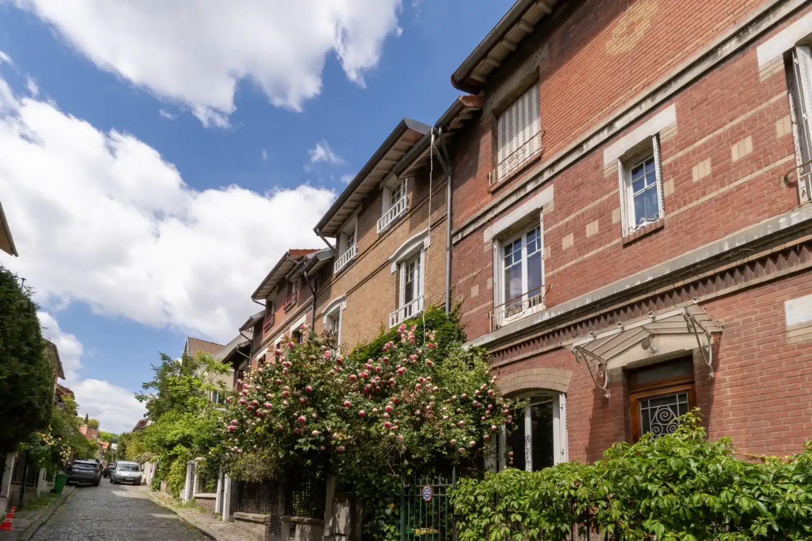 Façades de briques rouges bordant une ruelle pavée sous un ciel nuageux.