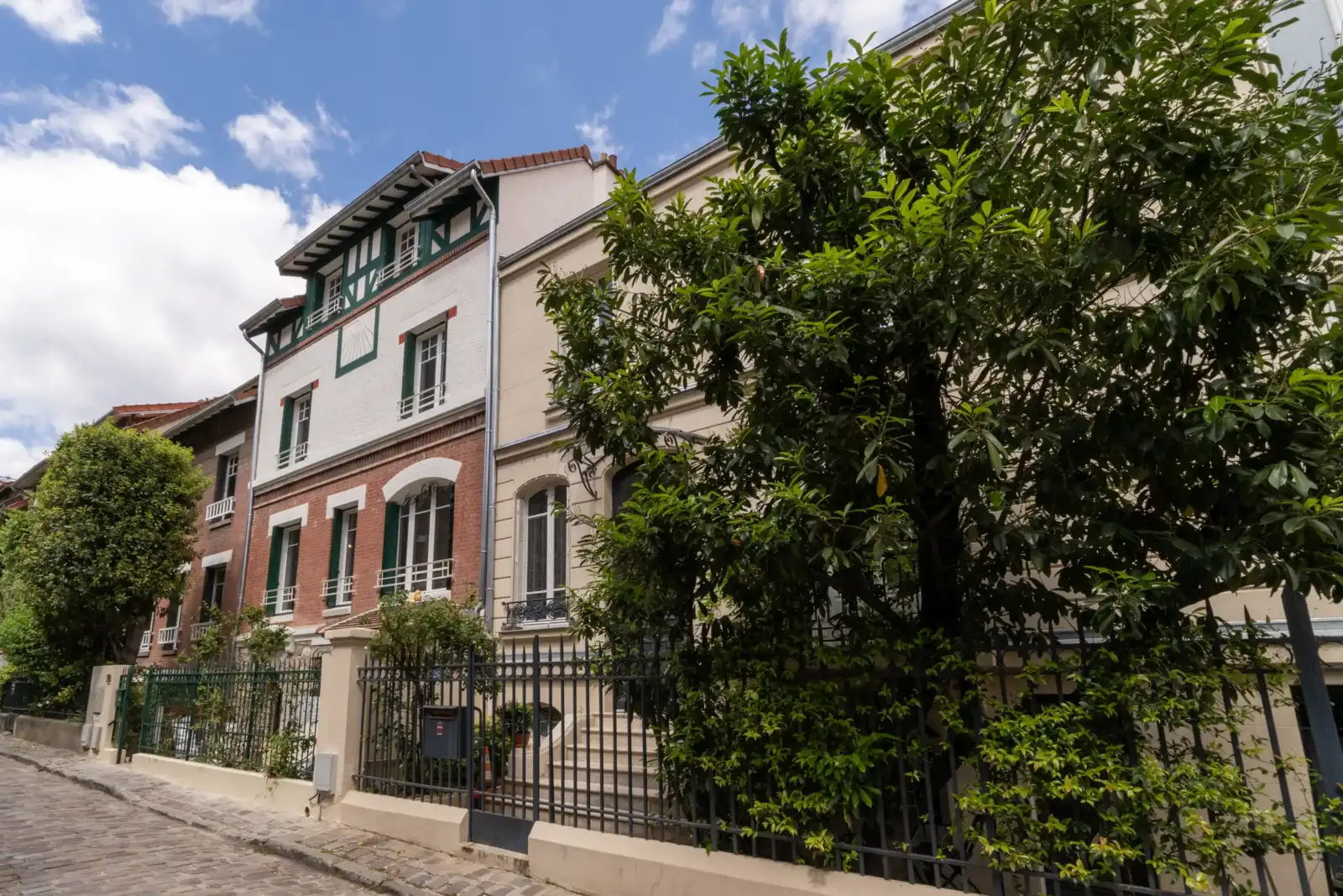 Une rue pavée bordée de charmantes maisons colorées et arborées dans le quatorzième arrondissement.