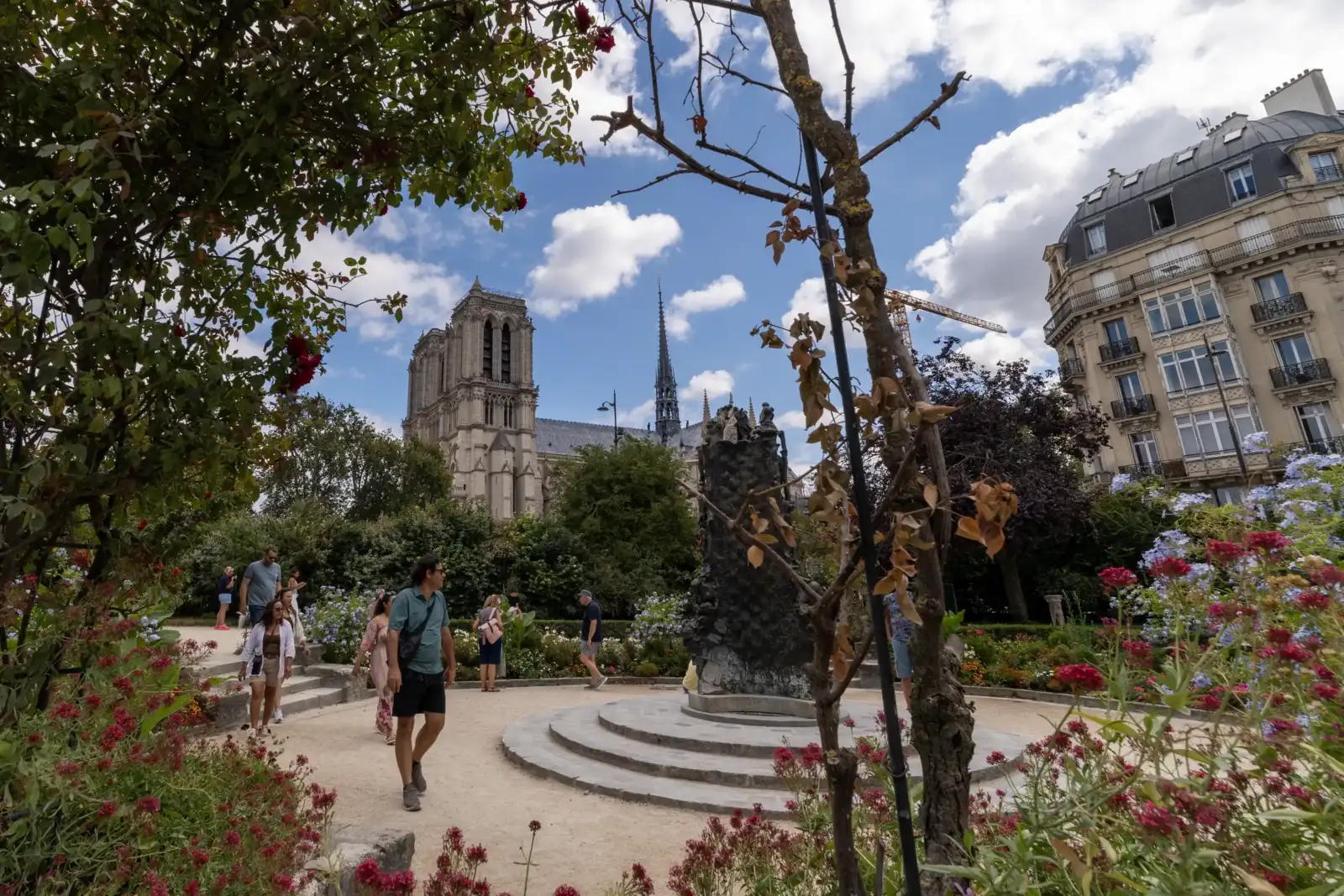 Des visiteurs se promènent dans le square René Viviani avec la cathédrale Notre-Dame en arrière-plan.