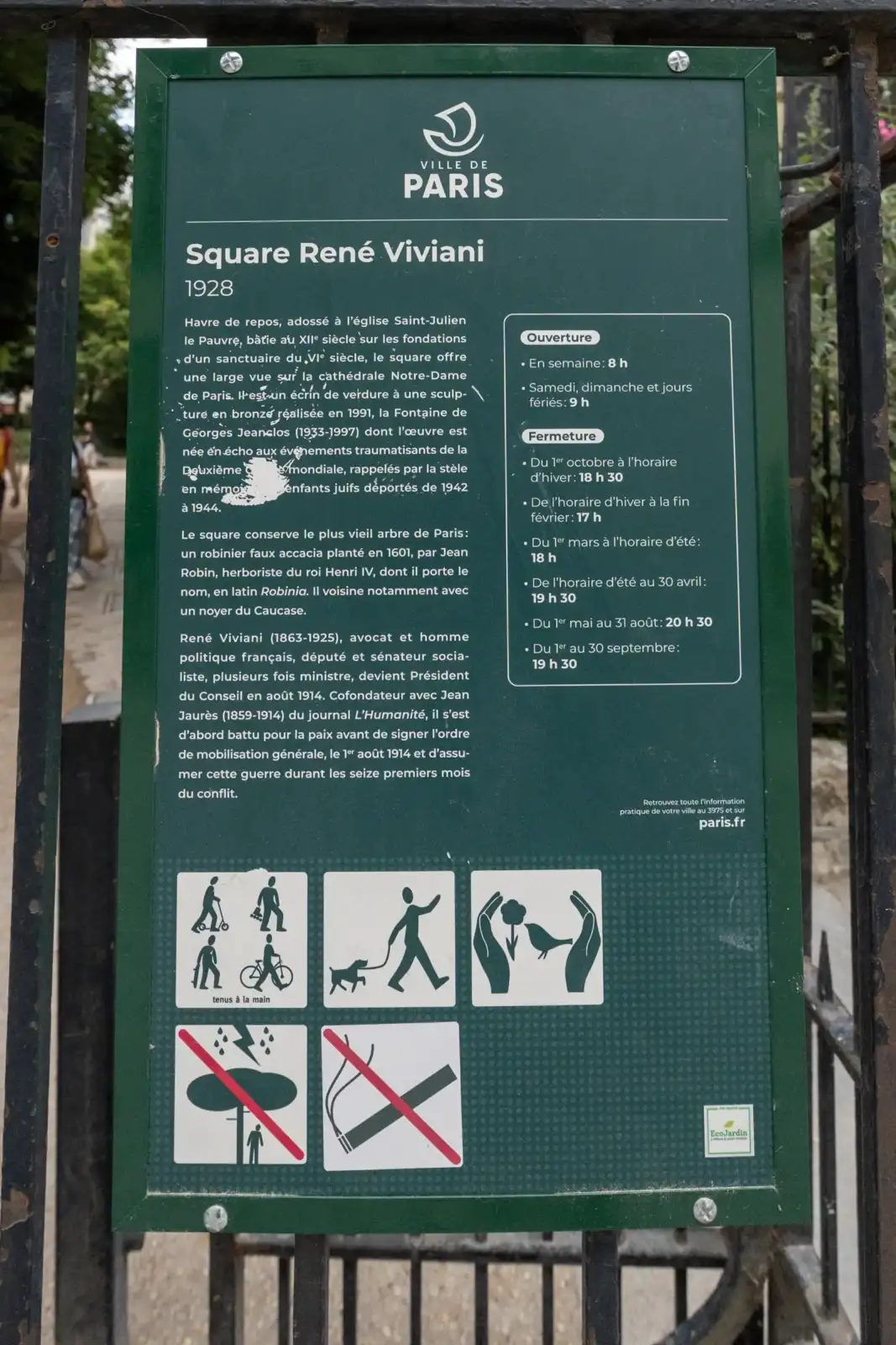 Un panneau vert de signalisation présente l'historique et les horaires du square René Viviani.