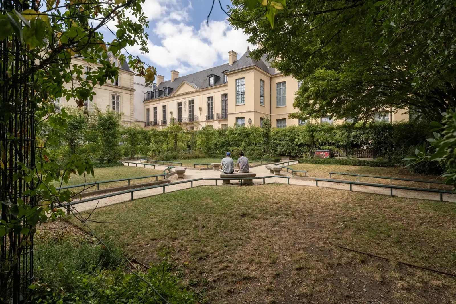 Deux personnes assises sur un banc dans le Square Saint-Gilles Grand-Veneur à Paris.