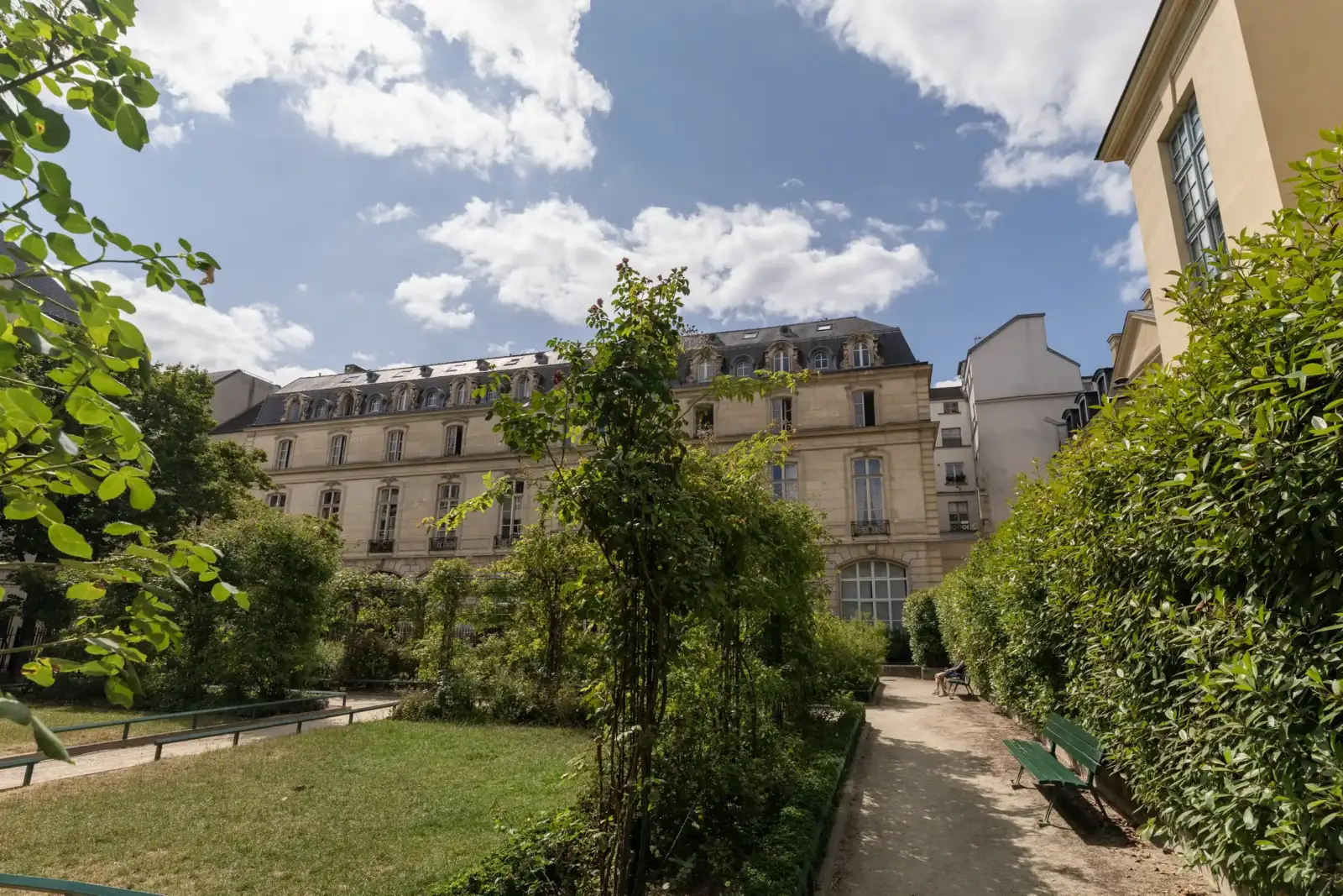 Une vue depuis le Square Saint-Gilles Grand-Veneur montrant la façade d'un bel immeuble parisien.