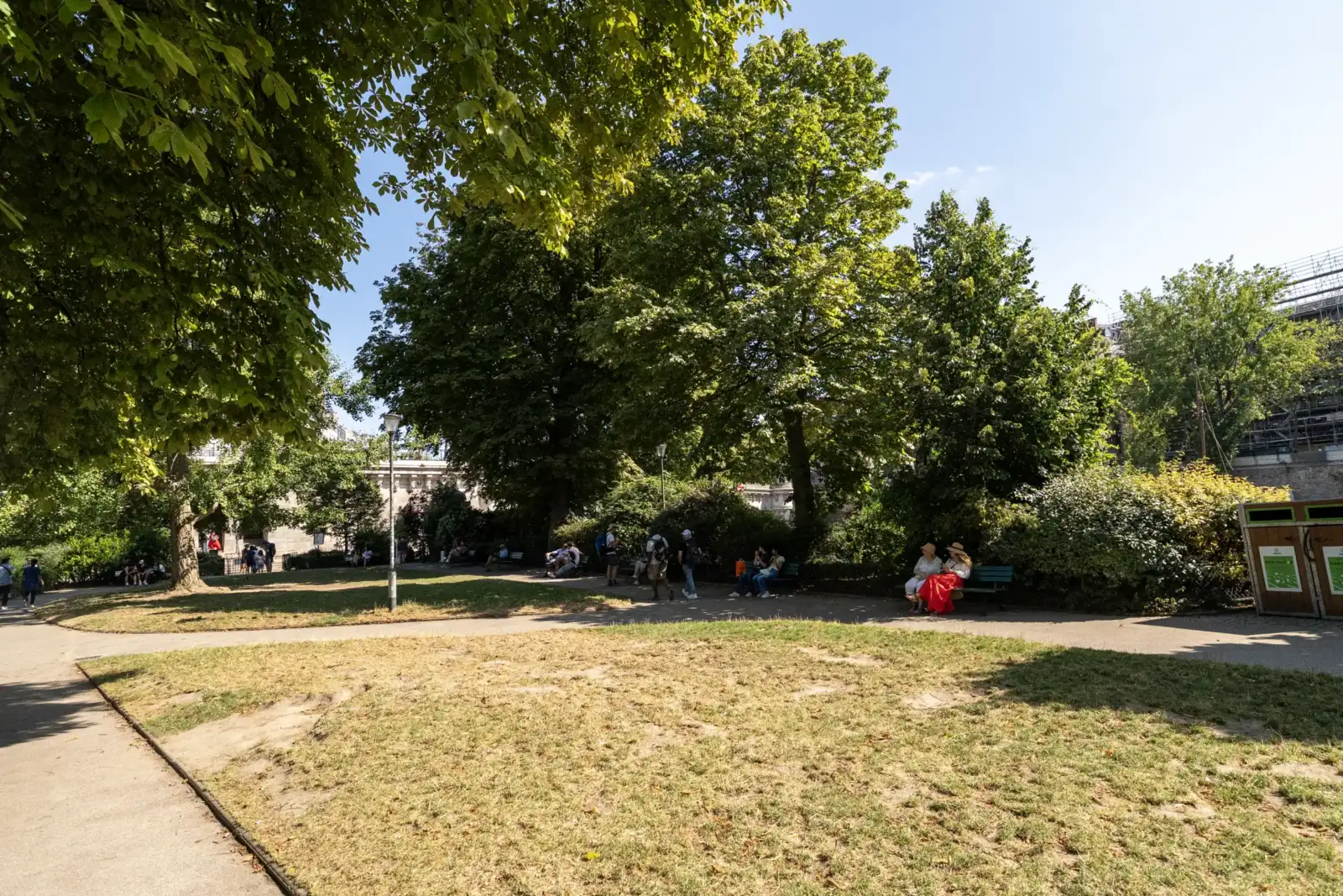Des visiteurs se promènent et se reposent au soleil dans le Square du Vert-Galant.