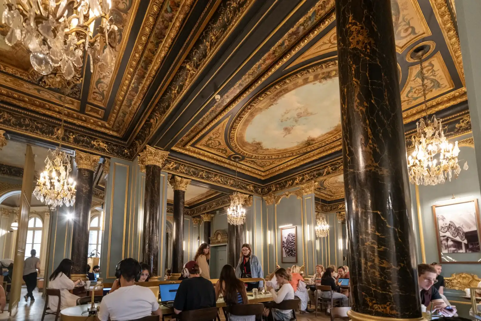 Vue intérieure somptueuse et élégante du Starbucks Opéra à Paris avec des clients attablés.