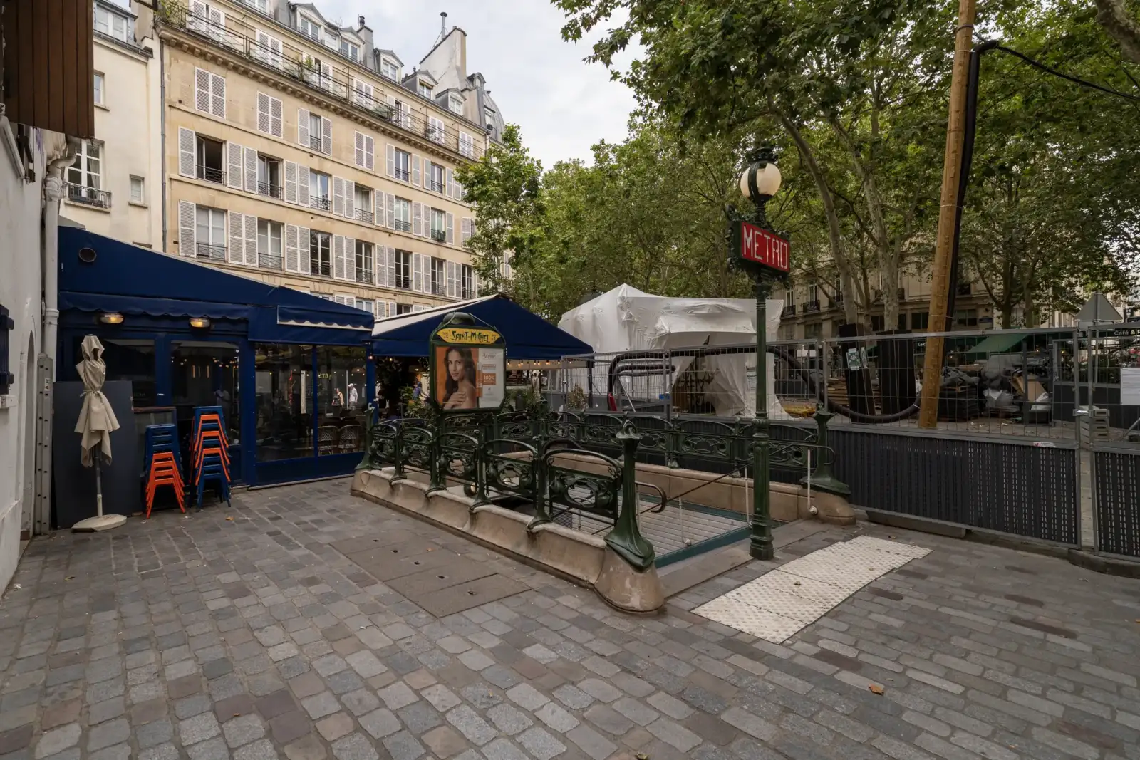 Entrée de la station de métro Saint-Michel à Paris bordée par des bâtiments haussmanniens.