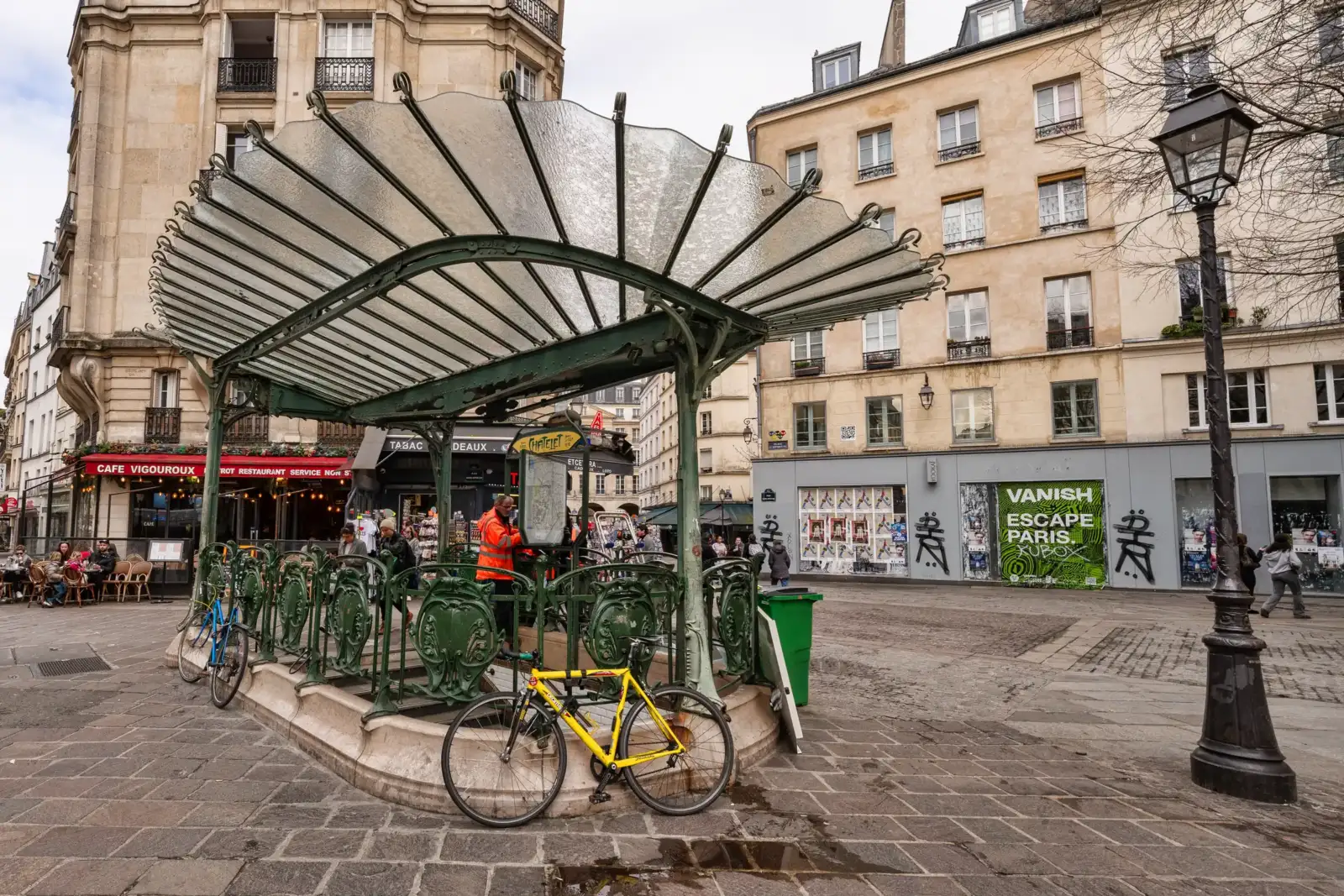 Une entrée de métro parisienne de style Art nouveau devant des immeubles en pierre.