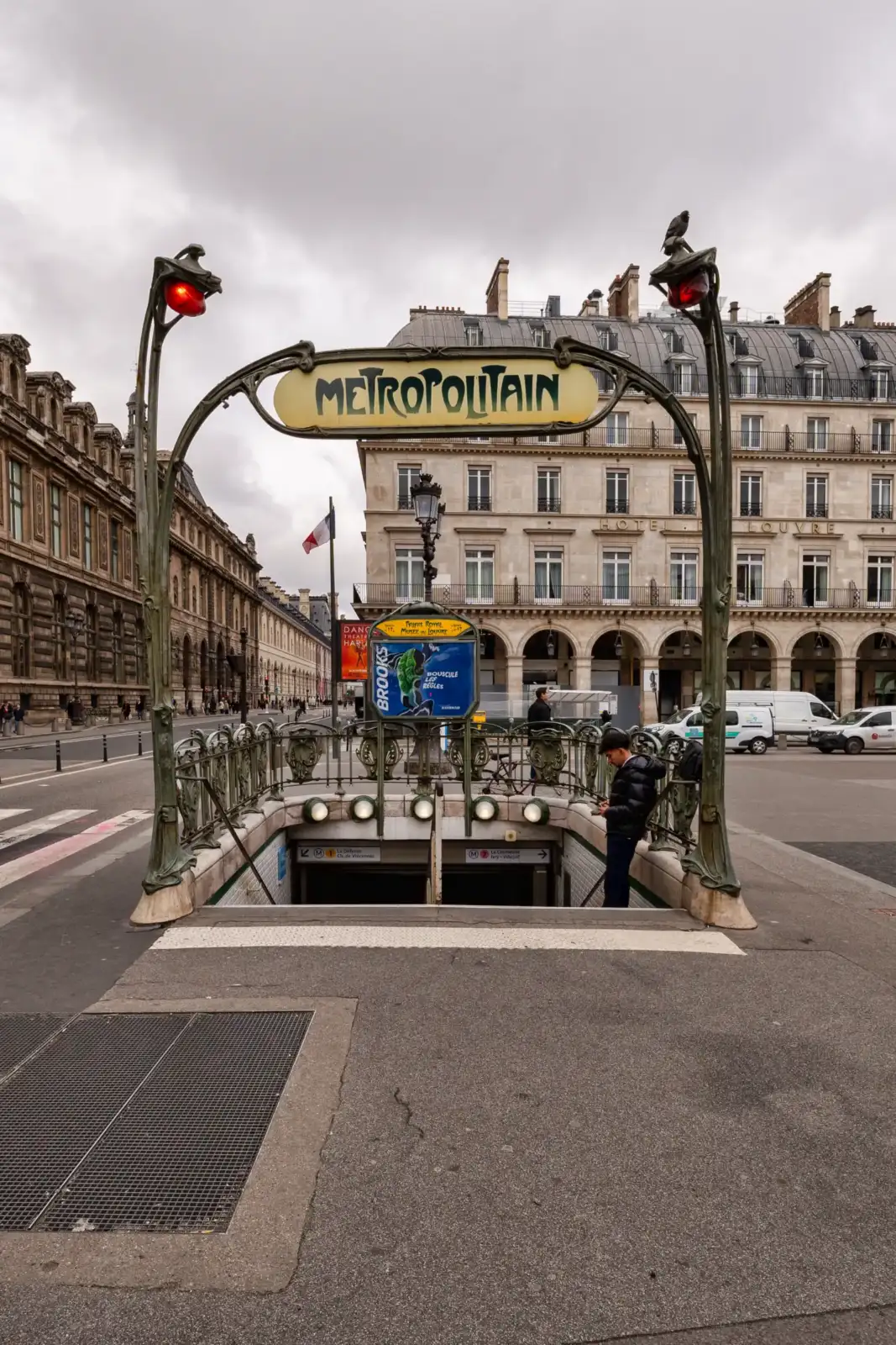 Une entrée de métro parisien style Art nouveau située devant un bâtiment historique classique.