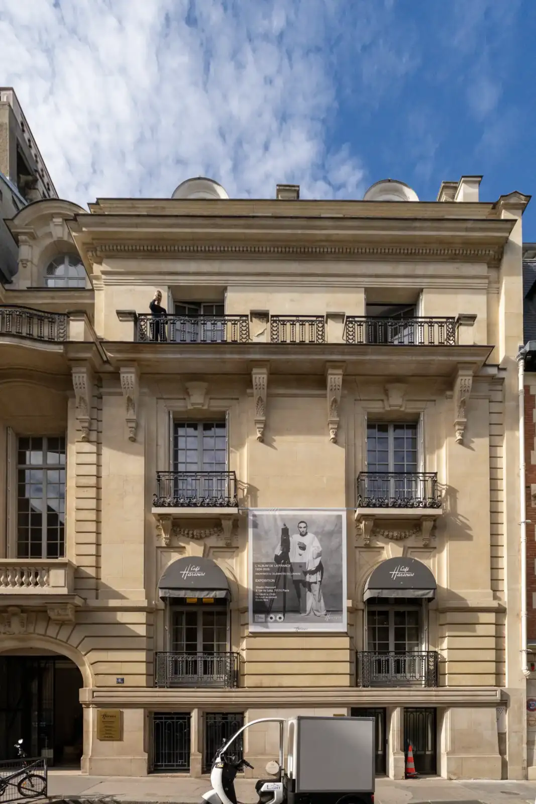 Façade haussmannienne en pierre du prestigieux Studio Harcourt avec une immense bâche publicitaire.