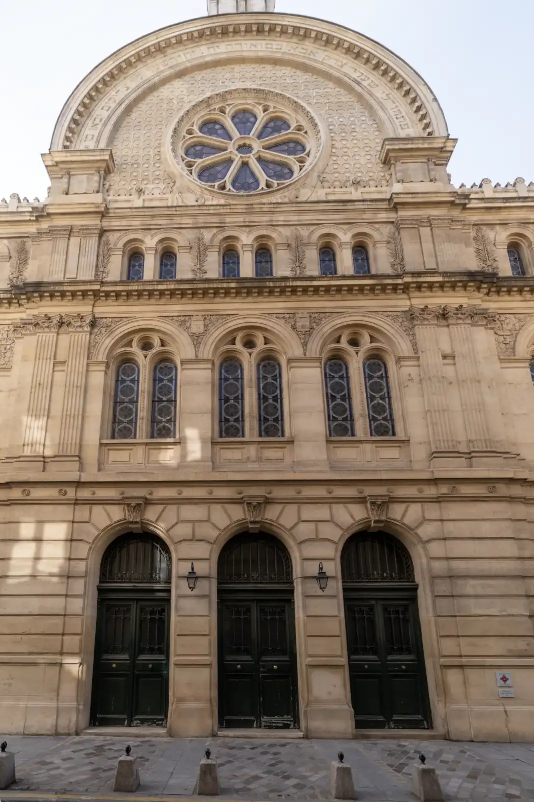 Façade en pierre de la synagogue des Tournelles avec ses arcades et sa grande rose.