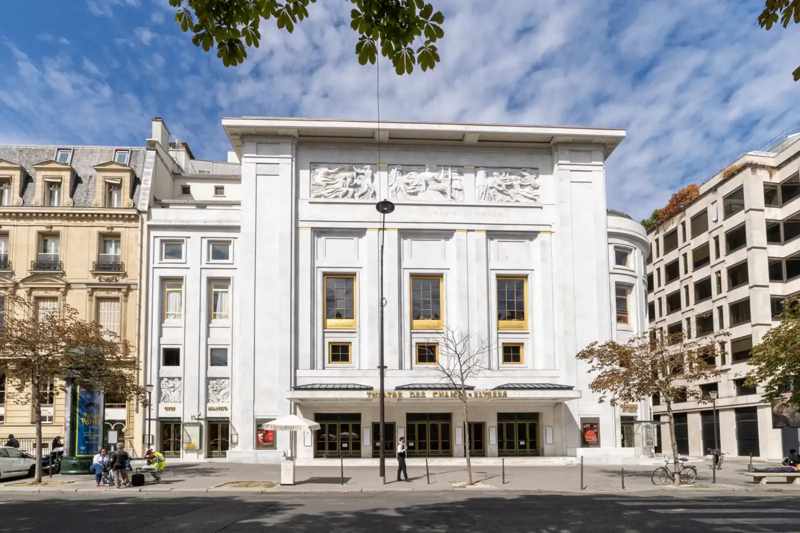 Vue de face du Théâtre des Champs-Élysées à Paris sous un ciel bleu nuageux.