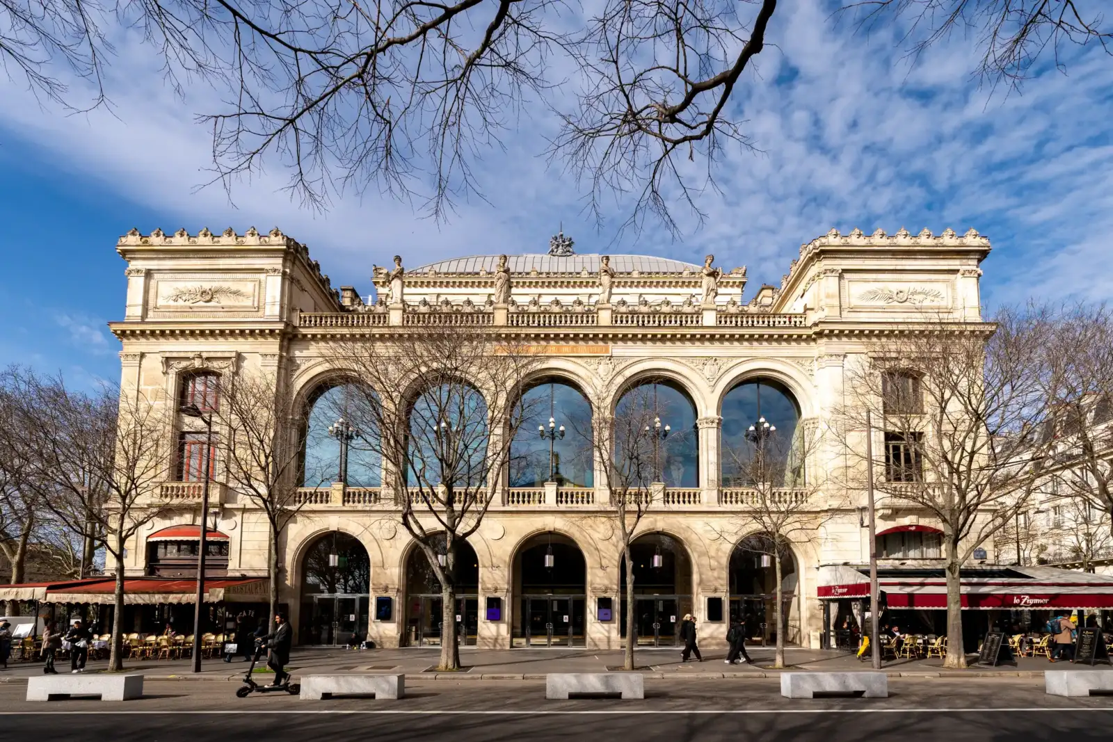 La façade classique du Théâtre du Châtelet à Paris sous un ciel bleu ensoleillé.