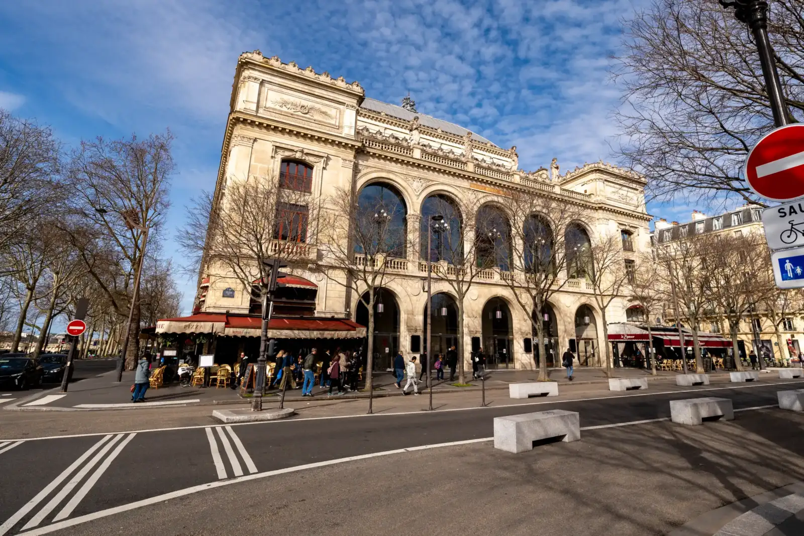 La façade monumentale du Théâtre du Châtelet domine une rue animée sous un ciel bleu.