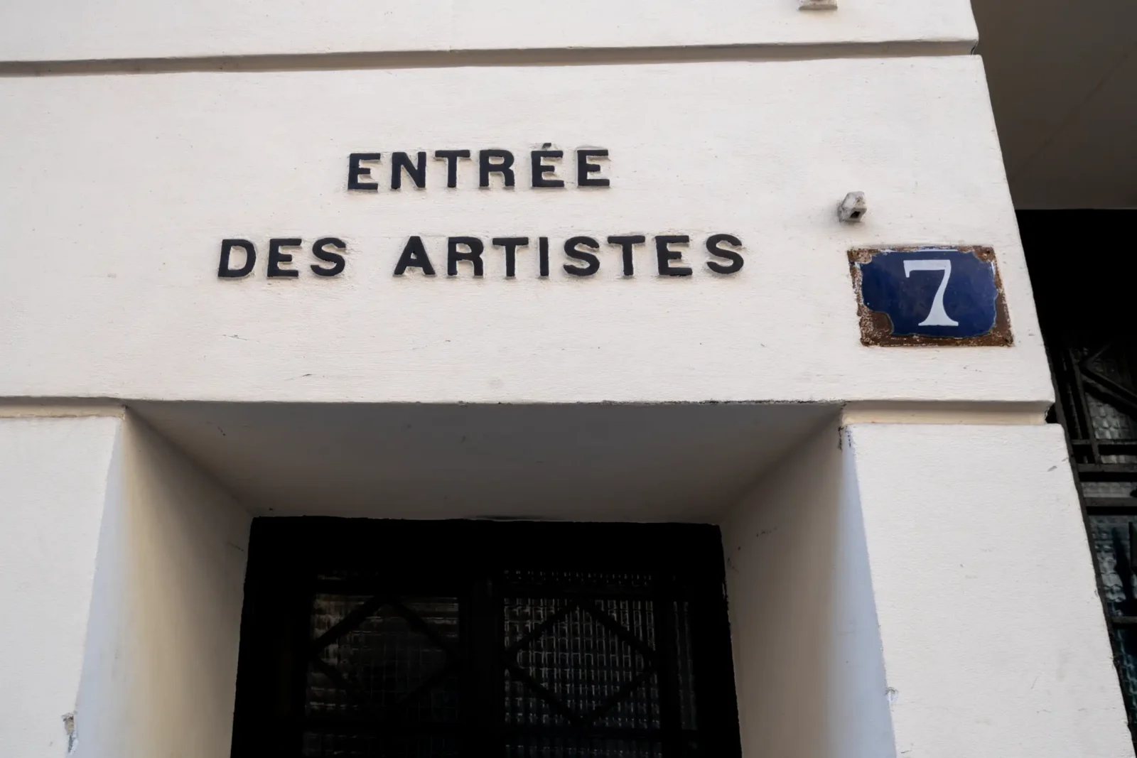 L inscription Entrée des artistes surplombe une porte noire avec une plaque numéro sept.