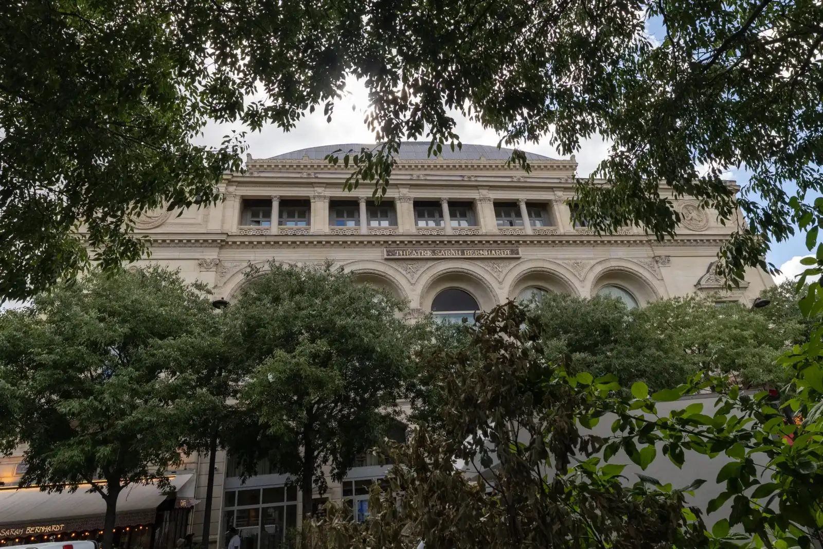 La façade classique du théâtre Sarah Bernhardt à Paris est encadrée par des arbres.
