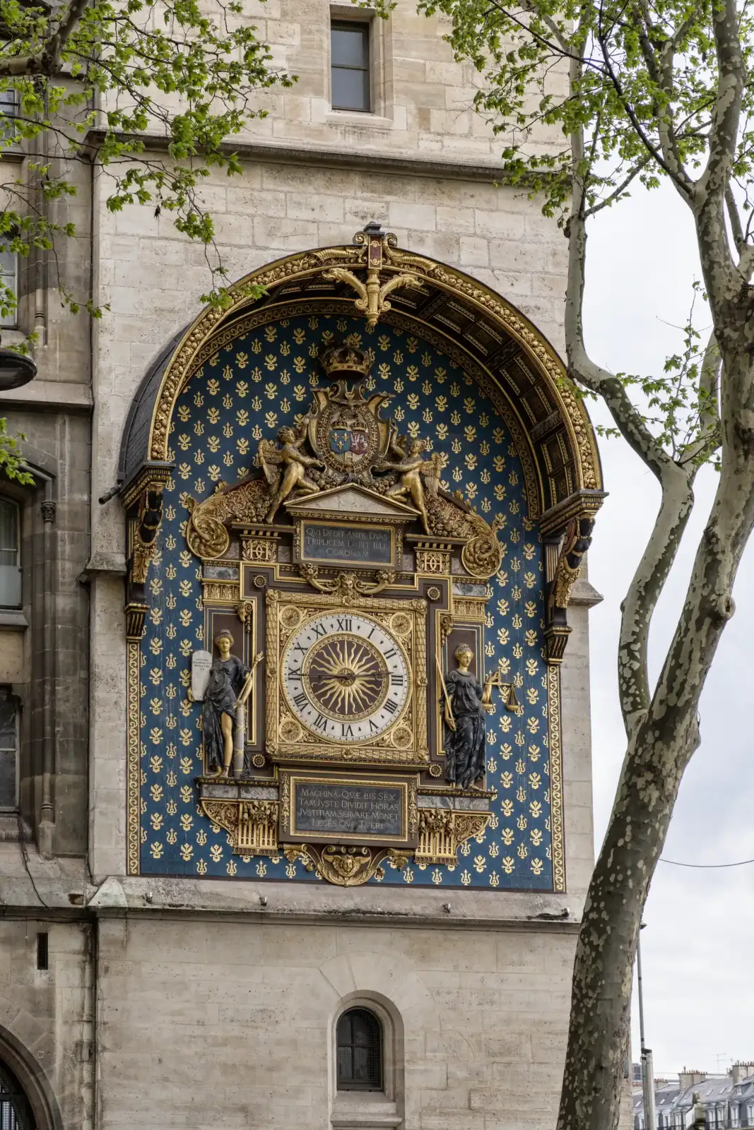 L'horloge dorée et ornée sur la façade en pierre de la Conciergerie à Paris.