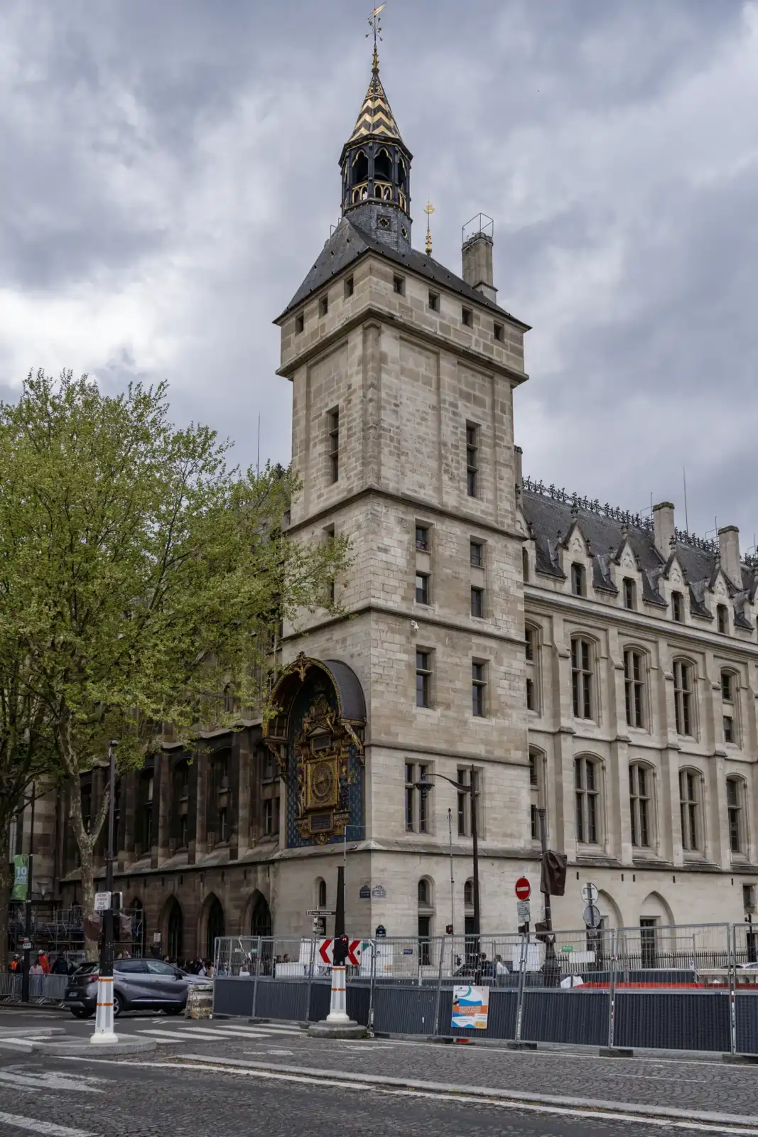 La tour de l'Horloge à Paris s'élève majestueusement sous un ciel gris nuageux.