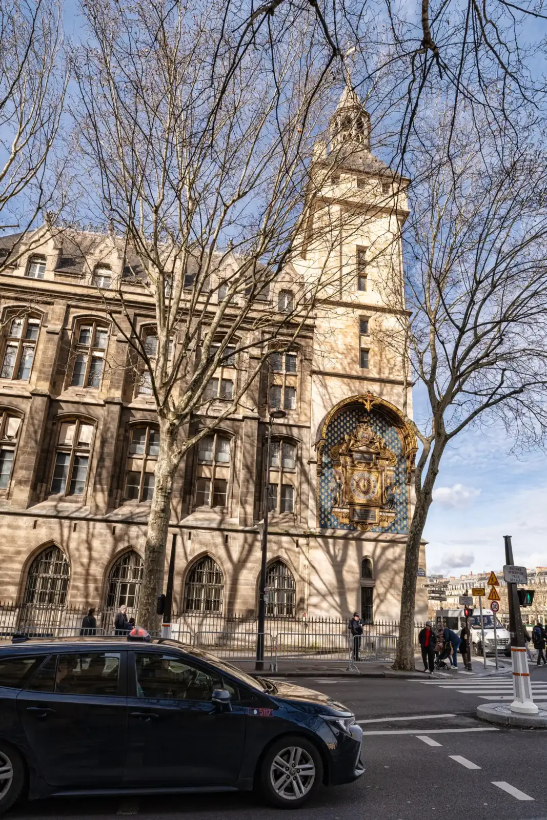 La façade historique de la Conciergerie avec son horloge dorée sous un ciel bleu.