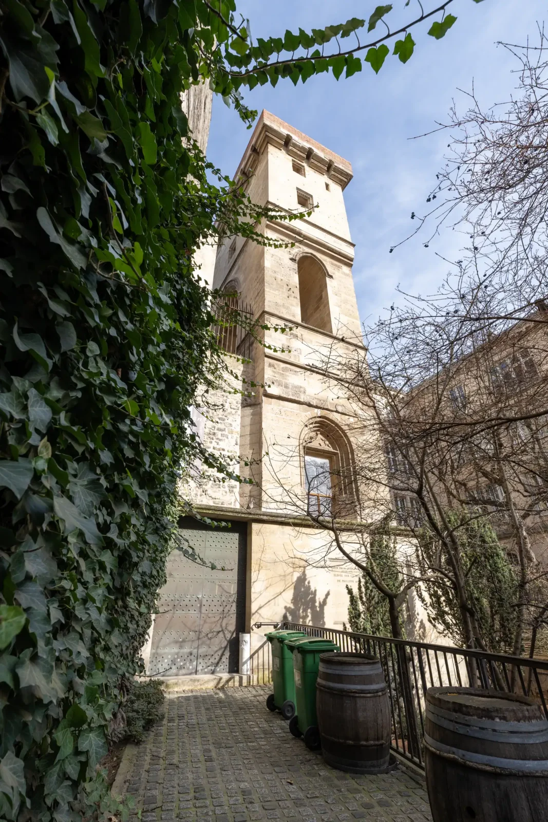 La tour médiévale Jean sans Peur s'élève au-dessus d'une cour pavée avec du lierre.