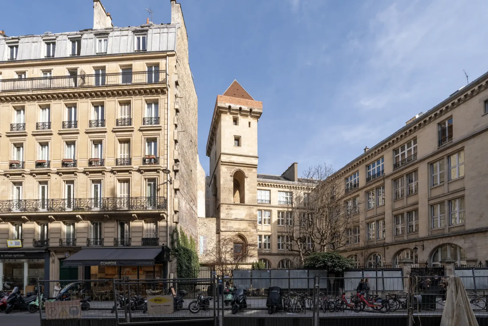 La tour Jean sans Peur s'élève entre des immeubles parisiens sous un ciel bleu.