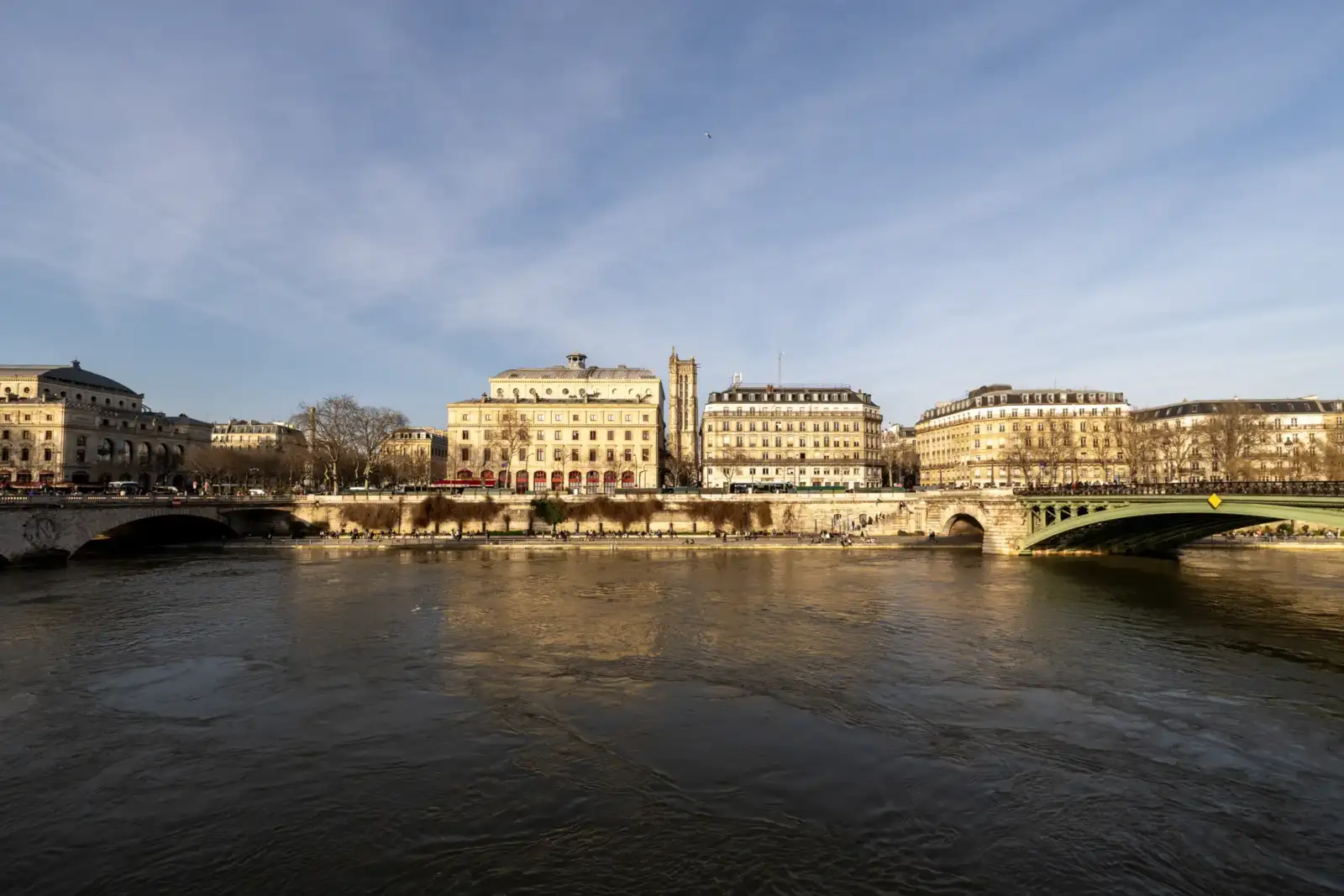 La Tour Saint-Jacques domine les quais de Seine sous un ciel bleu ensoleillé.