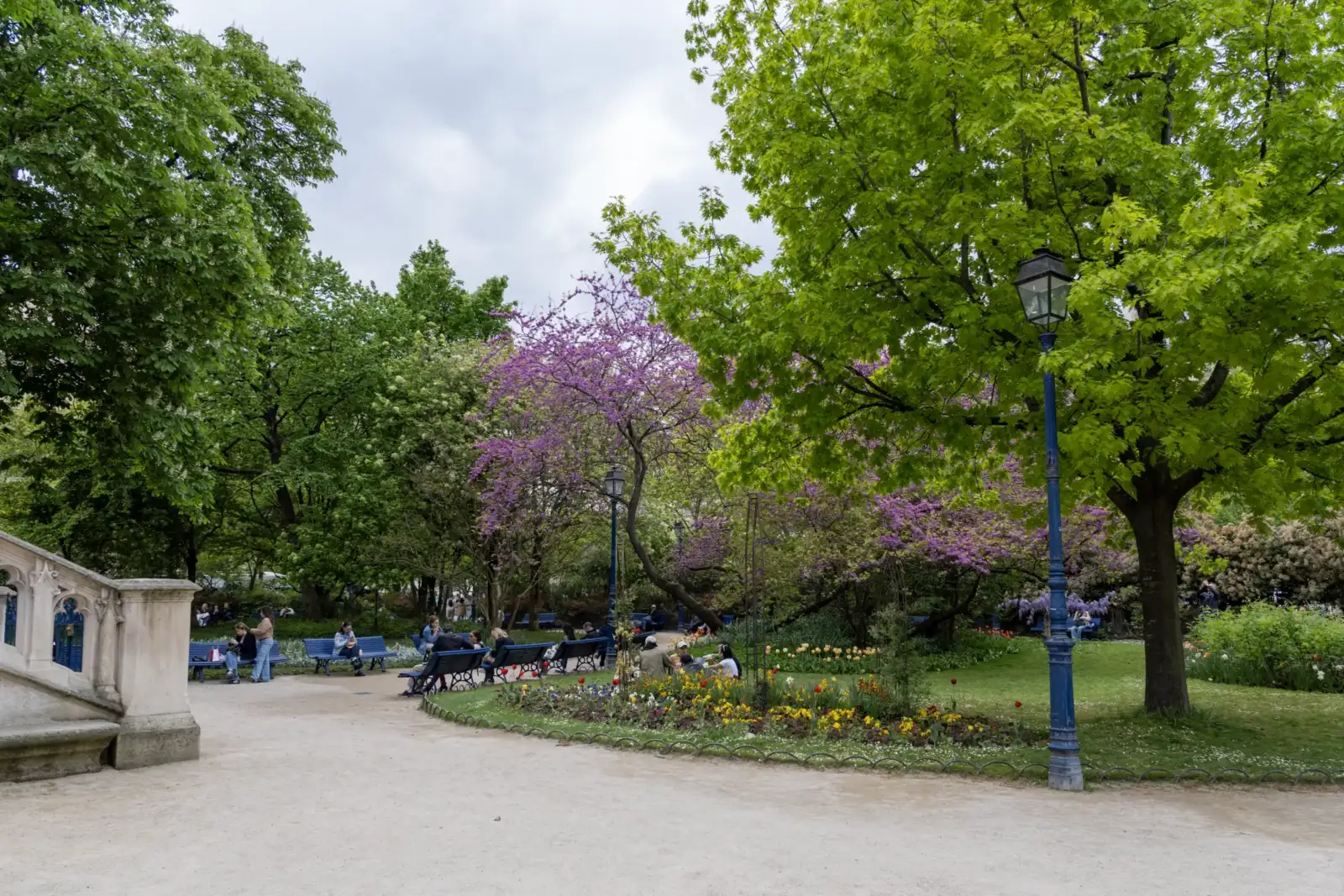 Des gens se détendent dans le parc verdoyant et fleuri de la Tour Saint-Jacques.