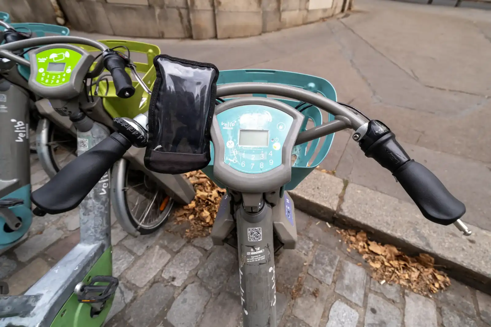 Vue en plongée du guidon d un Vélib turquoise garé sur un pavé parisien.