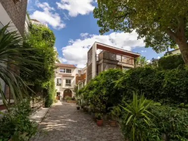 Une ruelle pavée et verdoyante de la villa Santos-Dumont à Paris.