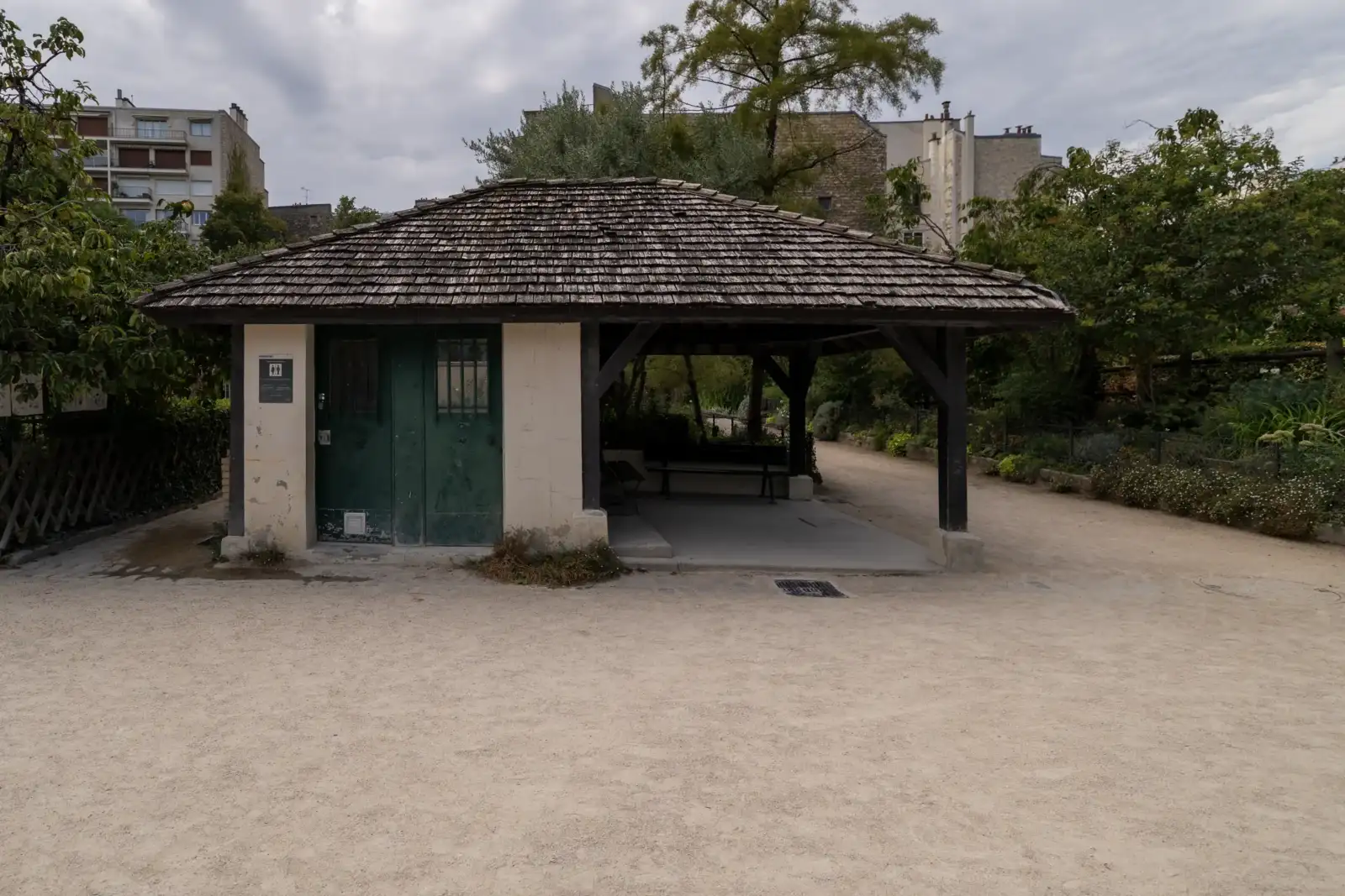 Une petite structure en bois avec des toilettes publiques et un abri ombragé.
